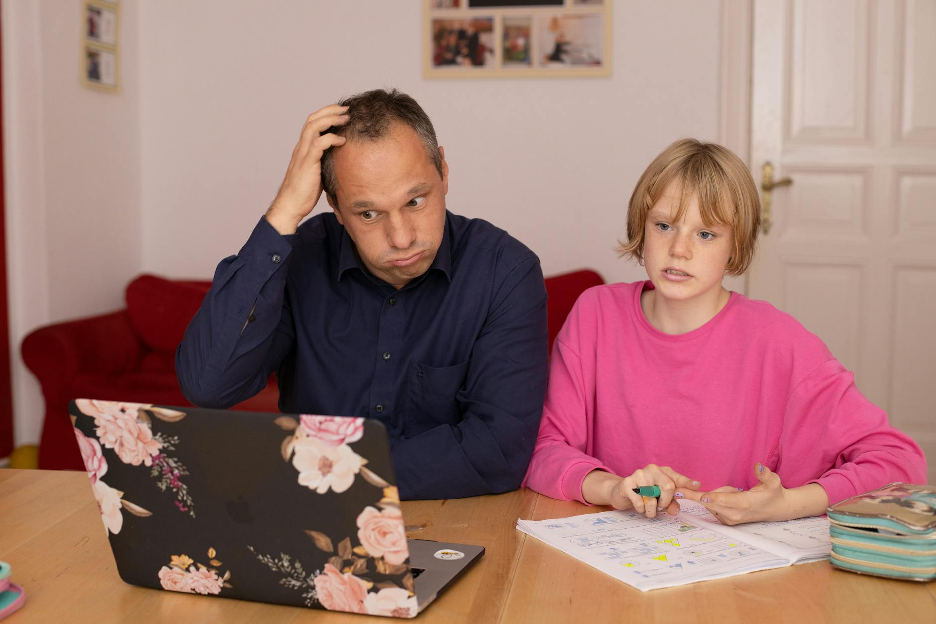 A father and daughter working on a laptop, focusing on home education activities.