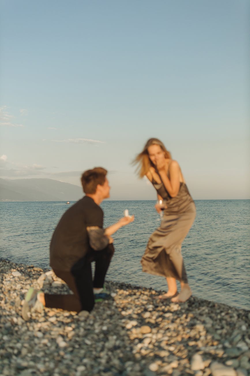A romantic marriage proposal on a beach during a stunning sunset.