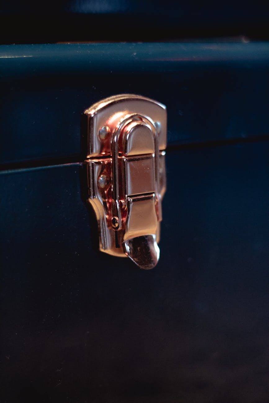 Detailed close-up of a metallic latch on a locked suitcase in a dark setting.